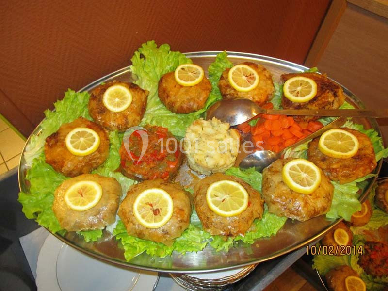 Plateau de boulettes de viande garnies de rondelles de citron, accompagné de légumes et de purée, sur un lit de salade.