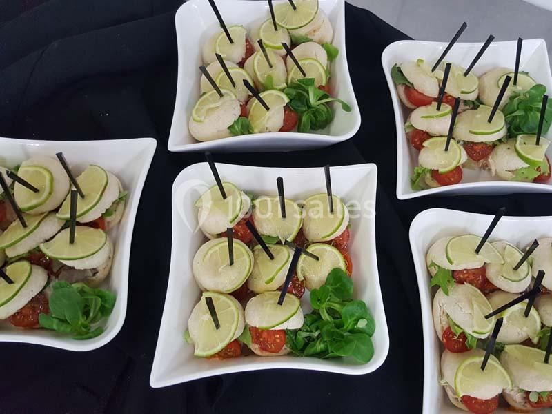 Brochettes apéritives avec tomates cerises, mozzarella, rondelles de citron vert et feuilles de salade, présentées dans des…