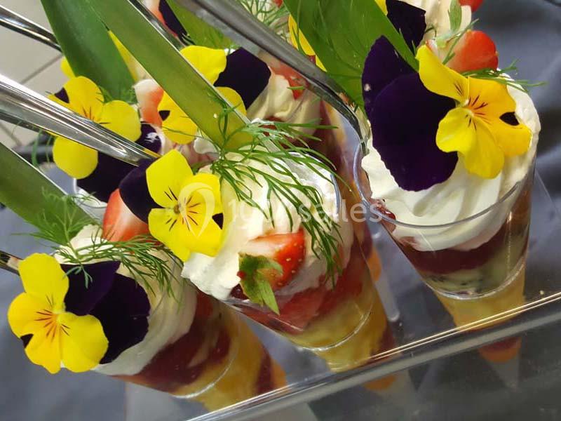 Desserts en verrines garnis de fruits frais, crème fouettée, herbes et fleurs comestibles colorées.