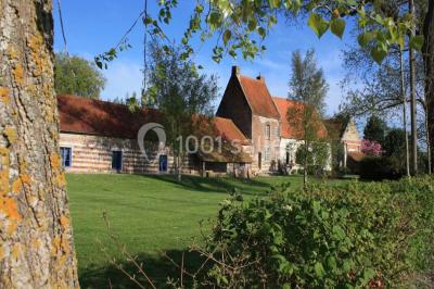 Miniature Location salle Clairmarais (Pas-de-Calais) - La Ferme de l'Abbaye #12 Tour en briques avec toit en ardoise, entourée de bâtiments ruraux et d'arbres, sous un ciel dégagé.