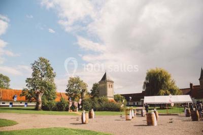 Miniature Location salle Clairmarais (Pas-de-Calais) - La Ferme de l'Abbaye #13 Tour en briques avec toit en ardoise, entourée de bâtiments ruraux et d'arbres, sous un ciel dégagé.