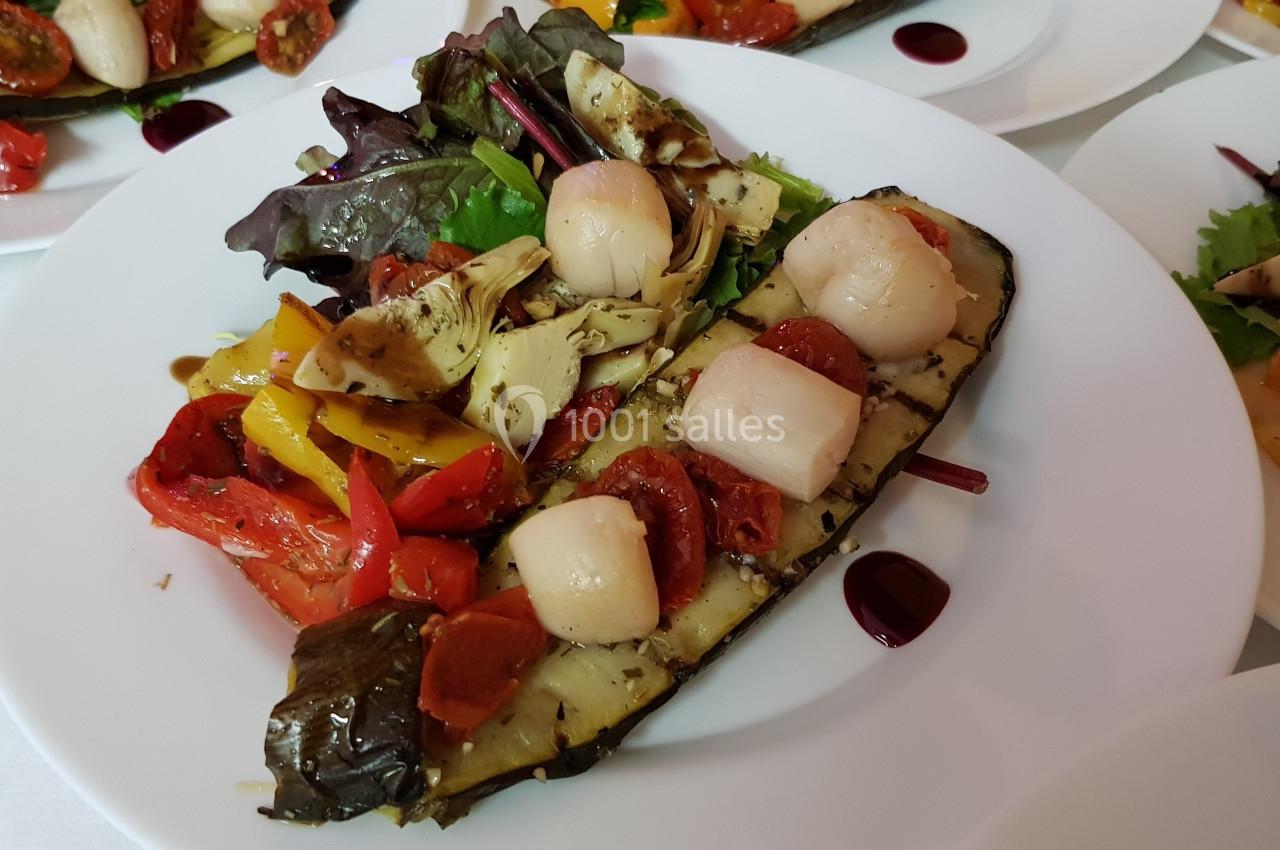 Assiette de légumes grillés avec noix de Saint-Jacques, accompagnée de salade et d'une sauce décorative.