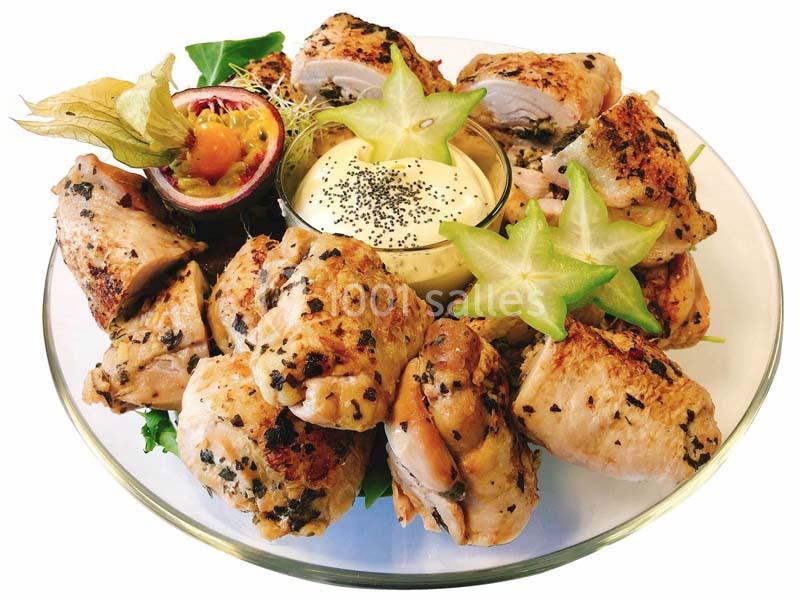 Assiette de roulés de poulet grillés avec sauce blanche, fruits exotiques et décoration de carambole.