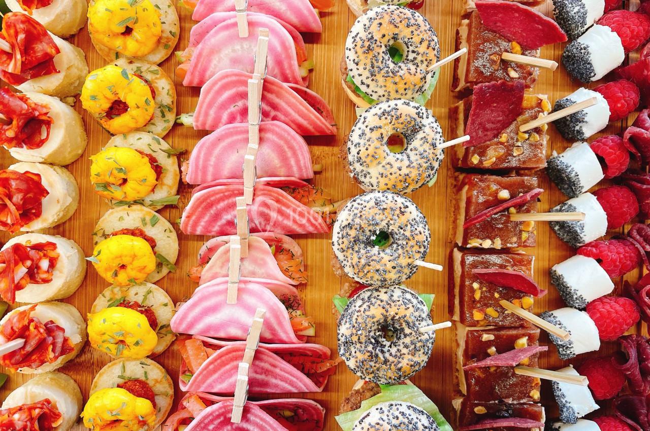 Plateau coloré de bouchées variées : mini-sandwichs, brochettes de fruits et amuse-bouches garnis.