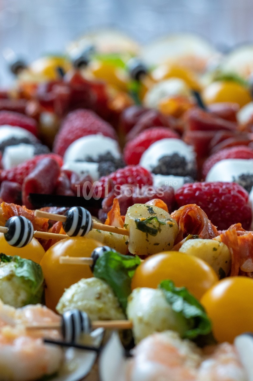 Assortiment de brochettes apéritives avec tomates cerises, fromage, fruits et charcuterie.