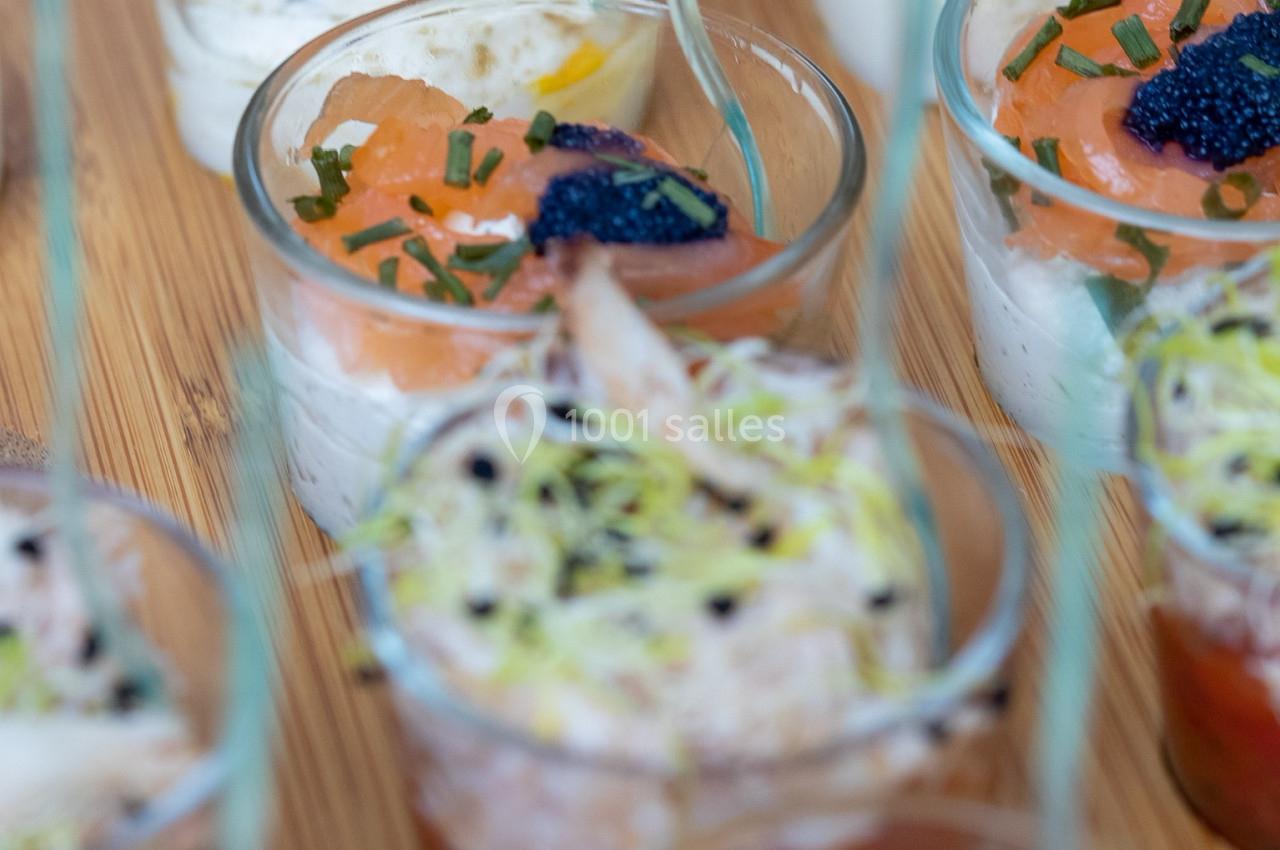 Verrines variées avec saumon, crème, herbes, œufs de poisson et garnitures, présentées sur un plateau en bois.