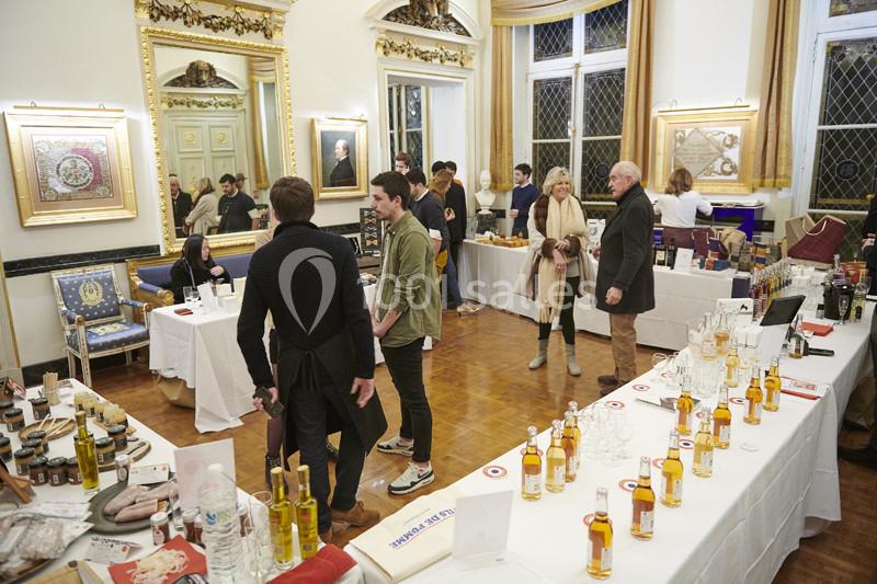 Des personnes visitent un salon dans une salle élégante, avec des stands présentant des produits artisanaux et des…