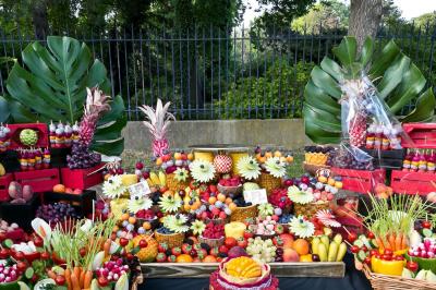 Table garnie de fruits variés et colorés, disposés artistiquement avec des feuilles tropicales en arrière-plan.