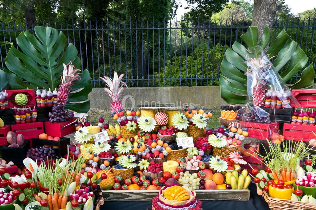 Table garnie de fruits variés et colorés, disposés artistiquement avec des feuilles tropicales en arrière-plan.
