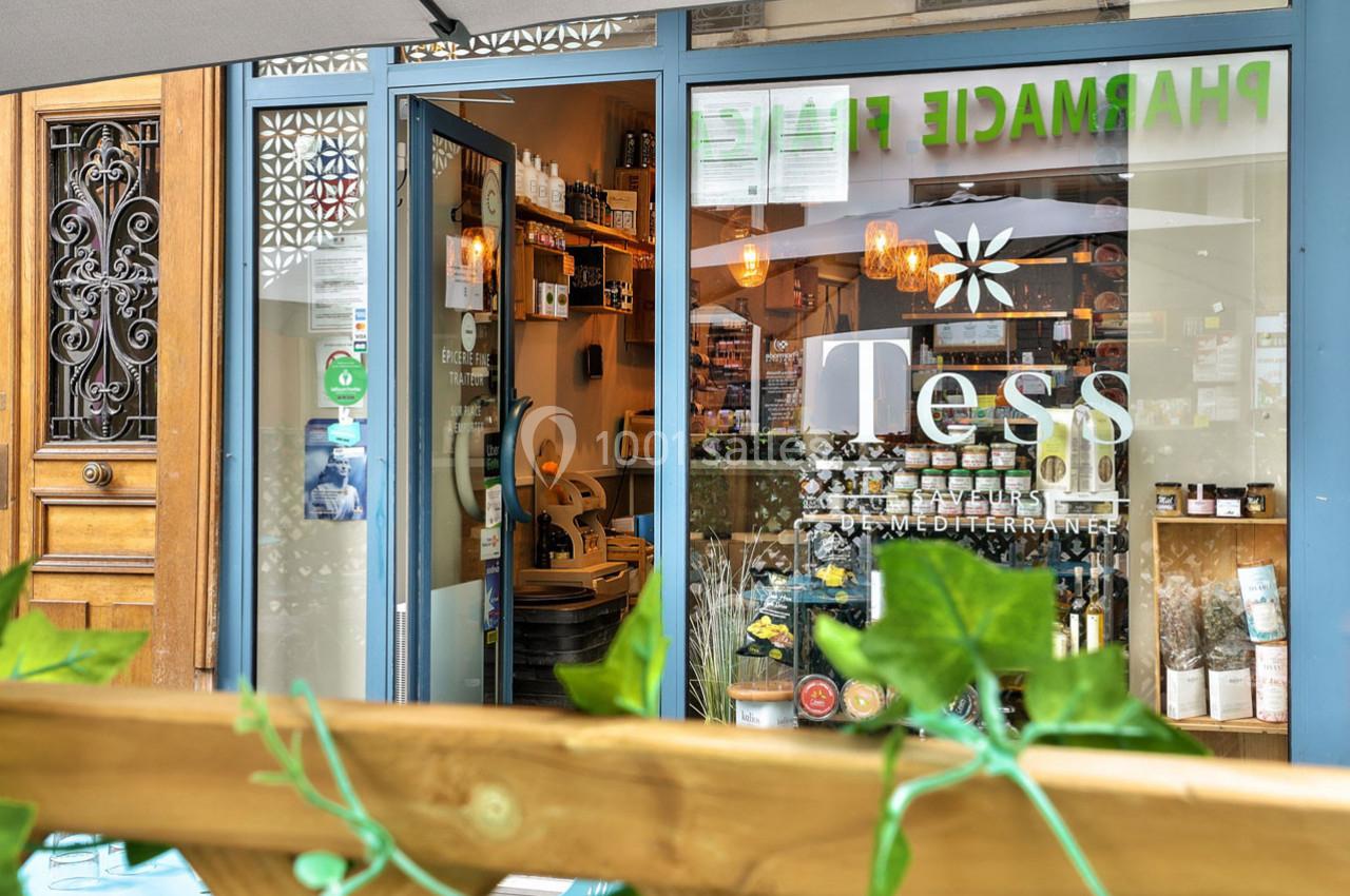 Façade d'une boutique avec vitrine affichant ’Tess’, entourée de plantes, et entrée ouverte sur un intérieur lumineux.