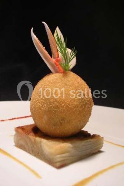 Boule panée garnie de pinces de crabe, posée sur une tranche de gratin, décorée d'aneth sur une assiette blanche.