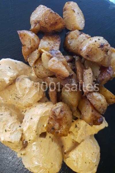 Assiette contenant des morceaux de poulet en sauce crémeuse et des pommes de terre rôties dorées.
