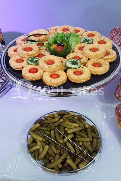 Plateau de biscuits salés garnis de tomates cerises et herbes, accompagné d'un bol de cornichons.