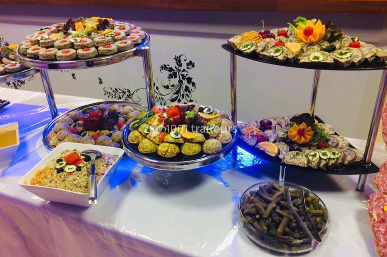 Buffet composé de plateaux de sushis, légumes farcis, salades et cornichons, présenté sur une table décorée.