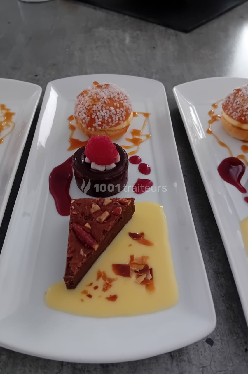 Assiette de desserts variés comprenant un brownie, une religieuse, un coulis de fruits rouges et une crème anglaise.