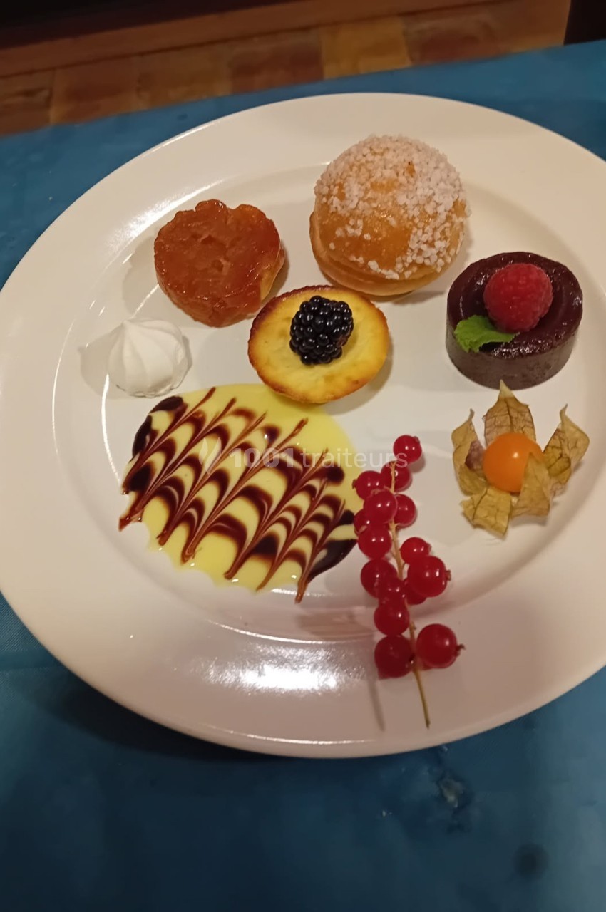 Assortiment de desserts sur une assiette blanche, incluant tartelette, fruits rouges, meringue et sauce décorative.