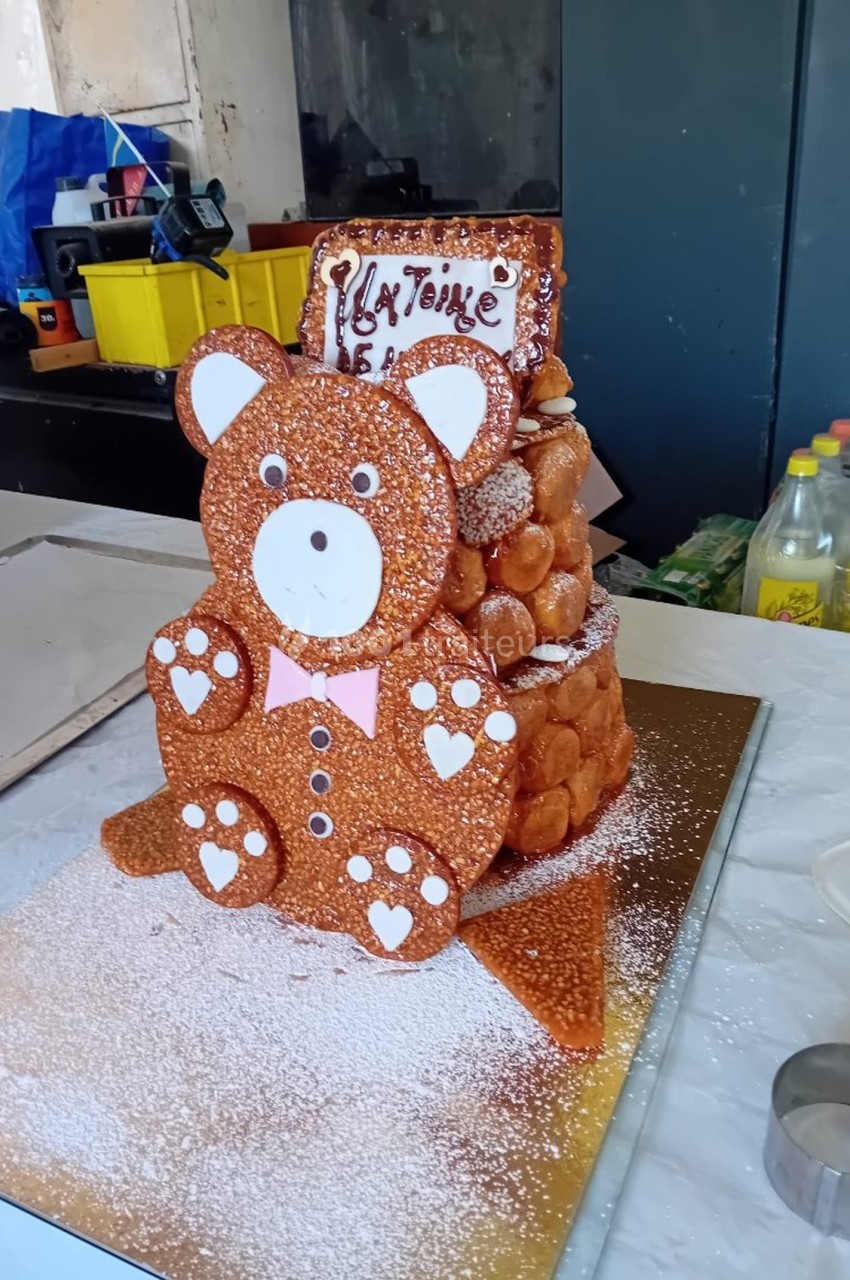Pièce montée en forme d'ourson en nougatine et choux, décorée de sucre glace et d'un message en chocolat.