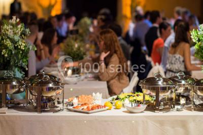 Miniature Traiteur Élancourt (Yvelines) - Sarah Lima Traiteur Brésilien #2 Salle de réception décorée avec des tables alignées, nappes blanches, chaises pliantes et ornements suspendus.