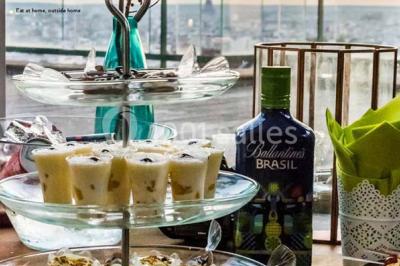 Miniature Traiteur Élancourt (Yvelines) - Sarah Lima Traiteur Brésilien #6 Salle de réception décorée avec des tables alignées, nappes blanches, chaises pliantes et ornements suspendus.