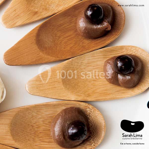 Cuillères en bois garnies de crème chocolatée et décorées d'une cerise noire sur un fond clair.