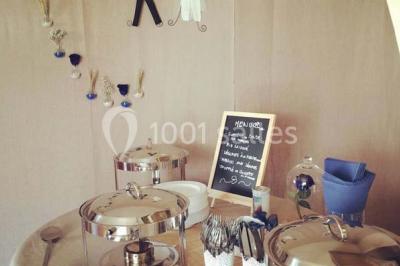 Miniature Traiteur Élancourt (Yvelines) - Sarah Lima Traiteur Brésilien #11 Salle de réception décorée avec des tables alignées, nappes blanches, chaises pliantes et ornements suspendus.