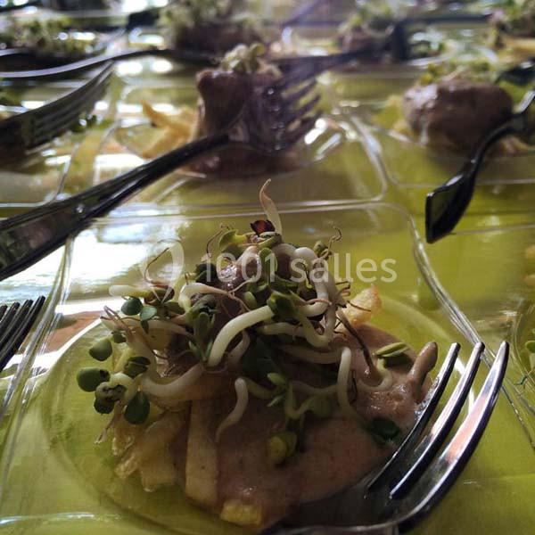 Assiette individuelle contenant des pousses germées sur une base de chips et sauce, avec des fourchettes noires.