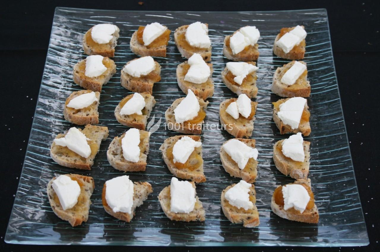 Tranches de pain garnies de fromage blanc et de confiture, disposées en rangées sur un plateau en verre.