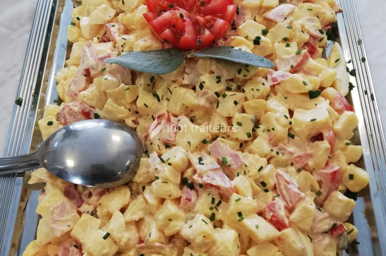 Salade de pommes de terre avec morceaux de tomates, ciboulette et mayonnaise, décorée d'une fleur de tomate.