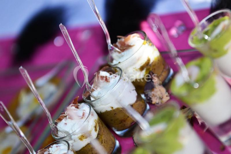 Verrines garnies de mousse, légumes et crème, présentées avec des cuillères sur une nappe rose.