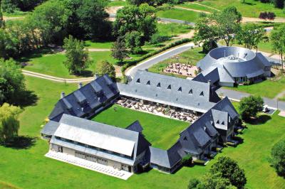 Terrasse en bois avec jacuzzi, deux fauteuils et table, offrant une vue sur un paysage verdoyant.