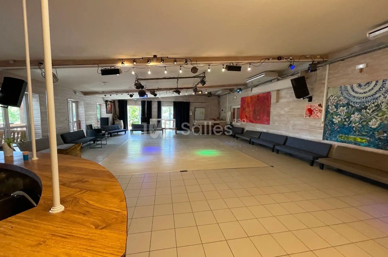 Salle spacieuse avec sol carrelé, banquettes le long des murs, éclairage suspendu et décorations murales colorées.
