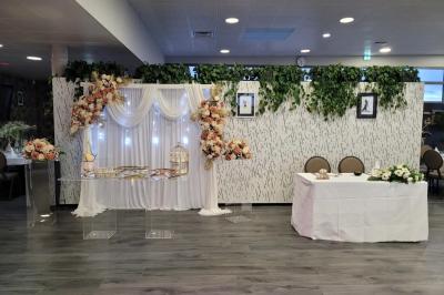 Salle de réception décorée avec des tables dressées, des chaises ornées de nœuds roses et des bouquets de fleurs.
