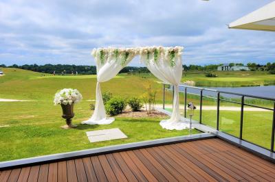 Salle de réception décorée avec des tables dressées, des chaises ornées de nœuds roses et des bouquets de fleurs.
