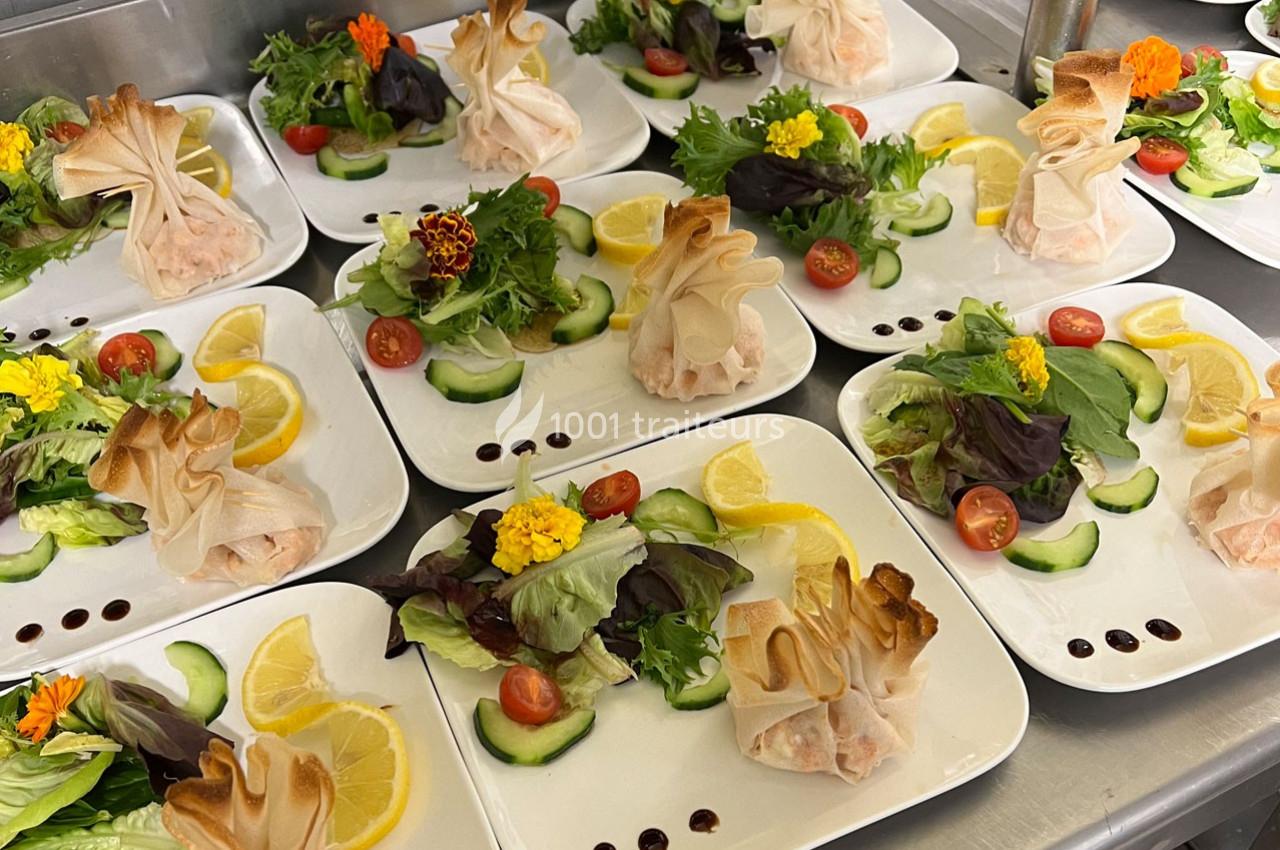 Assiettes dressées avec des aumônières dorées, salade verte, rondelles de concombre, tomates cerises et tranches de citron.