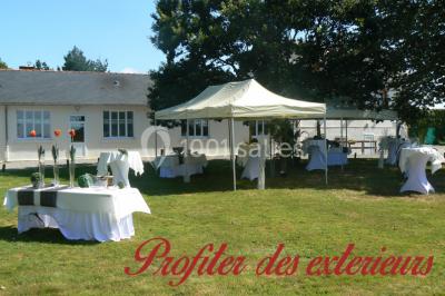 Miniature Location salle Chéméré (Loire-Atlantique) - La Baronnerie #20 Tente blanche montée sur une pelouse, équipée de tables hautes, devant un bâtiment clair et des arbres.