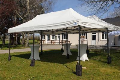 Miniature Location salle Chéméré (Loire-Atlantique) - La Baronnerie #21 Tente blanche montée sur une pelouse, équipée de tables hautes, devant un bâtiment clair et des arbres.