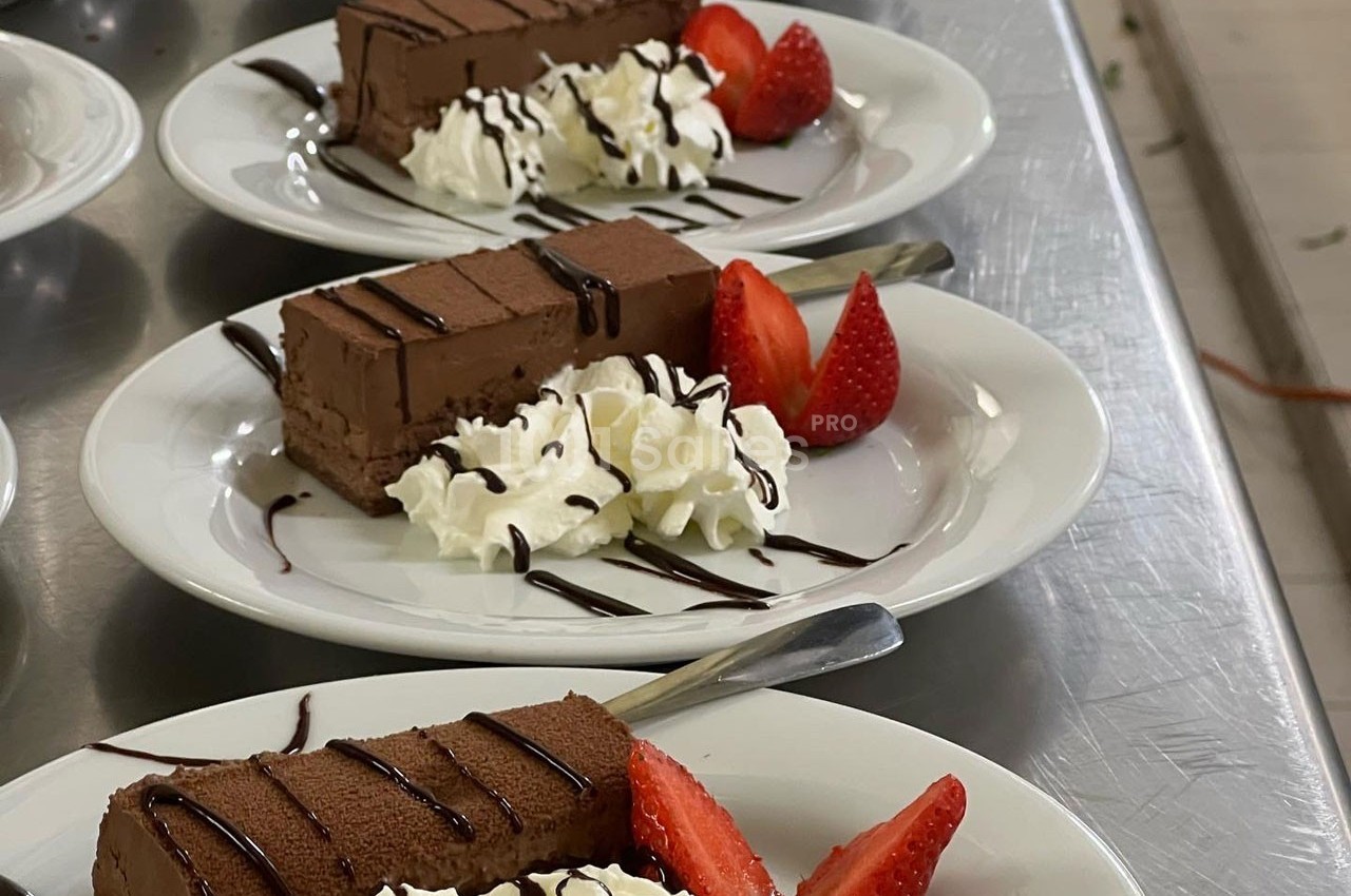 Assiettes de dessert avec parts de gâteau au chocolat, chantilly, fraises fraîches et filet de sauce chocolat.