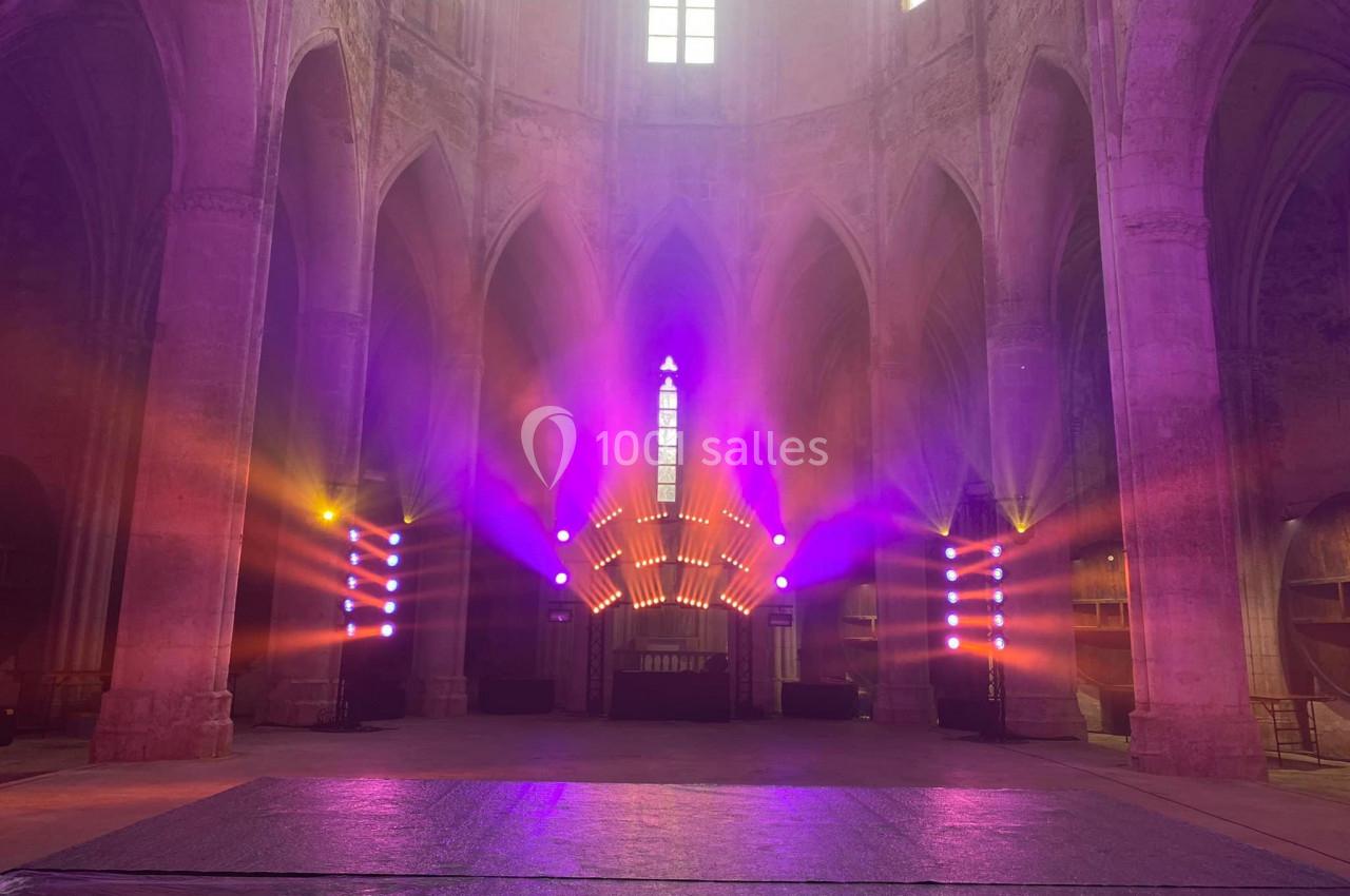 Éclairage coloré et lumineux dans une église gothique, mettant en valeur les arches et les vitraux.
