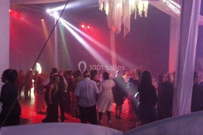 Groupe de personnes dans une salle éclairée par des lumières roses, certaines tenant des bougies.