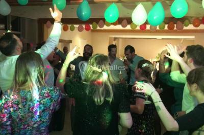 Groupe de personnes dans une salle éclairée par des lumières roses, certaines tenant des bougies.
