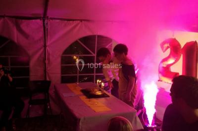 Groupe de personnes dans une salle éclairée par des lumières roses, certaines tenant des bougies.