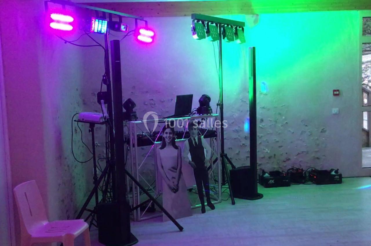 Installation de matériel de sonorisation et éclairage coloré dans une salle avec murs en pierre apparente.