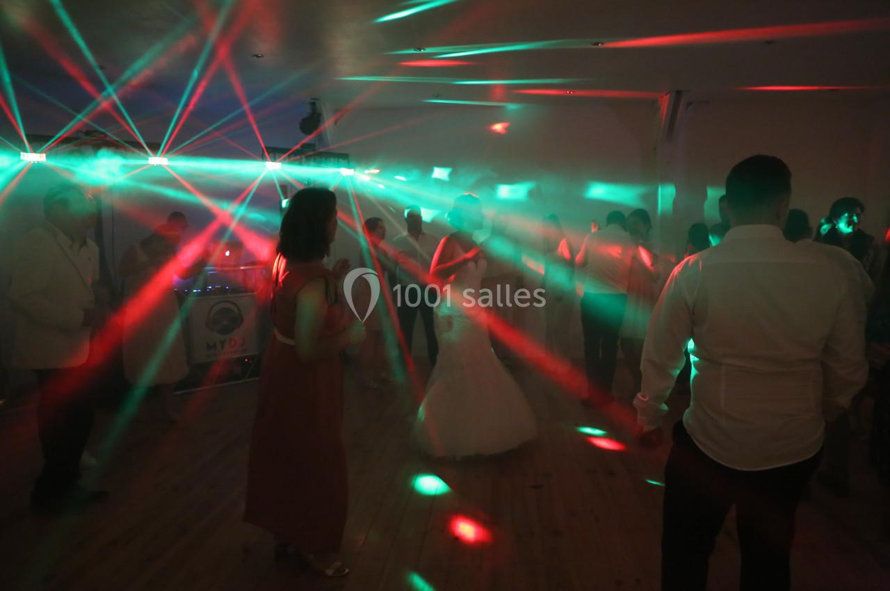 Des invités dansent dans une salle sombre illuminée par des faisceaux lumineux rouges et verts.