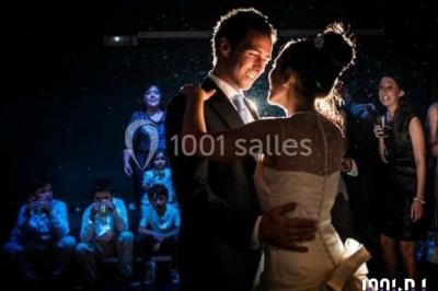 Un couple en tenue de mariage pose devant des lumières colorées dans une ambiance festive.