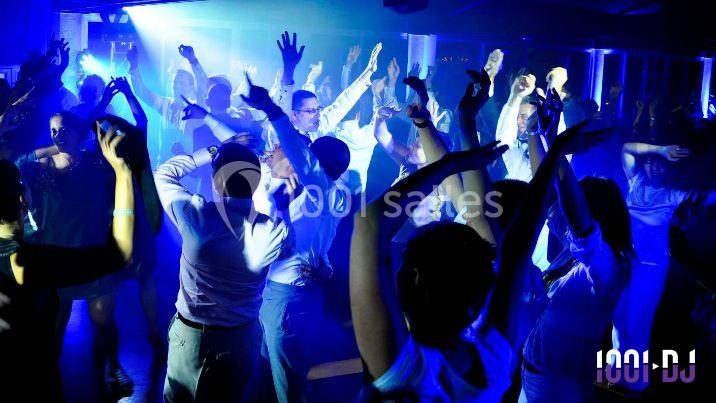 Personnes dansant sous des lumières bleues dans une ambiance festive en soirée.