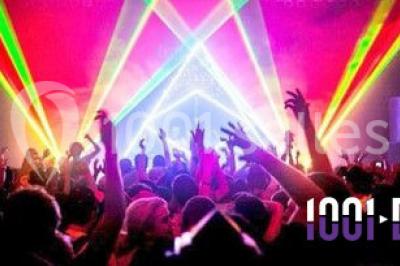 Un couple en tenue de mariage pose devant des lumières colorées dans une ambiance festive.