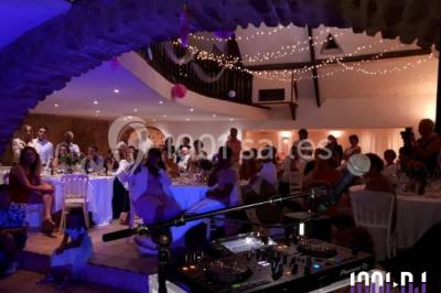 Un couple en tenue de mariage pose devant des lumières colorées dans une ambiance festive.