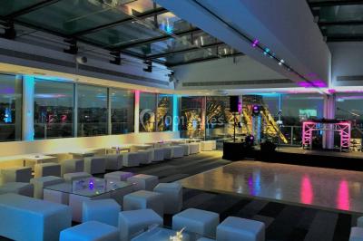 Un couple en tenue de mariage pose devant des lumières colorées dans une ambiance festive.