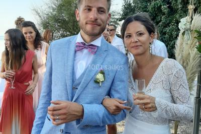 Un couple en tenue de mariage pose devant des lumières colorées dans une ambiance festive.