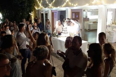 Un couple en tenue de mariage pose devant des lumières colorées dans une ambiance festive.